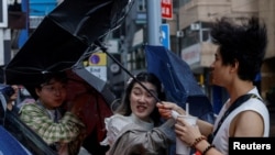 2023 年 10 月 8 日，在颱風“小犬” 逼近香港時，當地人頂著雨傘頂著強風行走。