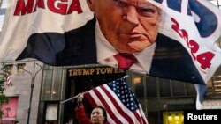 Seorang pendukung mantan Presiden AS Donald Trump mengibarkan bendera nasional AS di Trump Tower di New York City, Minggu 1 Oktober 2023.