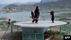 Sejumlah anak-anak tampak bermain trampolin di dekat Danau Shuhada di Kabul, Afghanistan, pada 2 Mei 2023. (Foto: AFP/Wakil Kohsar)