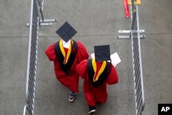 Dua mahasiswa sedang berjalan menuju gedung wisuda di AS pada 13 Mei 2018. (Foto: AP)