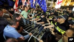 Opponents of "the Russian law" try to remove a police barrier outside the Parliament building in Tbilisi, Georgia, April 28, 2024. Clashes erupted between police and demonstrators protesting a new bill intended to track foreign influence.