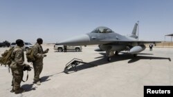 FILE - U.S. Army soldiers look at an F-16 fighter jet during an official ceremony to receive four such aircraft from the United States, at a military base in Balad, Iraq, July 20, 2015.