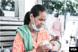 អ្នកស្រី គឹម សន កំពុងបំបៅទឹកដោះគោឆៅដល់ចៅប្រុស បន្ទាប់ពីទទួលបានការពិគ្រោះព្យាបាលជំងឺនៅមន្ទីរពេទ្យគន្ធបុប្ផា ក្នុងរាជធានីភ្នំពេញ កាលពីថ្ងៃទី ១ ខែមីនា ឆ្នាំ ២០២៣។ (ទែន សុខស្រីនិត/វីអូអេ)