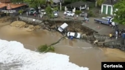 Esta imagen proporcionada por el gobierno de Sao Paulo muestra vehículos de caídos de una zona desmoronada junto a la playa en Sao Sebastiao, al este de Sao Paulo, Brasil, el domingo 19 de febrero de 2023, tras una fuerte tormenta en la zona