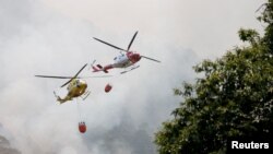 Firefighting helicopters fly over Aguamansa, as wildfires rage out of control on the island of Tenerife, Canary Islands, Spain, Aug. 18, 2023.