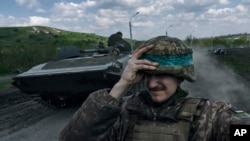 2023年4月26日，一名乌克兰士兵在乌克兰顿涅茨克地区巴赫穆特乘坐装甲运兵车时手扶头盔。（美联社照片）