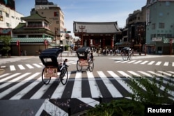 Rickshaws drive past the Kaminarimon at the Asakusa district in Tokyo, June 18, 2023.