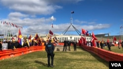 在澳大利亚国会大厦外的草坪上，欢迎和抗议中国总理李强访问的人群被分隔在隔离带两侧。（2024年6月17日）