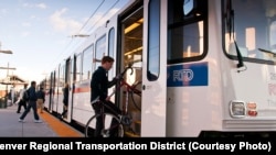 FILE — A passenger carries a bicycle onto a light rail train in Denver, Colorado, where public transit system fares will drop to zero for the month of August, when pollution levels are highest.