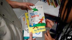 Tim McNeeley, left, helps students pick books to read during an after-school literacy program in Atlanta, April 6, 2023.