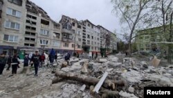 Stanovnici Slavjanska, u istočnoj Ukrajini, ispred zgrade razrušene u ruskom napadu (Foto: Donetsk Regional Military-Civil Administration/Handout via REUTERS)