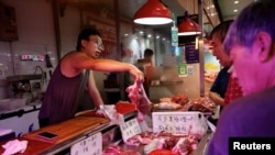 FILE - A pork vendor attends to a customer at a morning market in Beijing, China August 9, 2023.