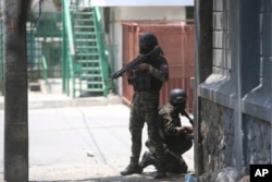 Polisi berlindung selama operasi antigeng di dekat Istana Nasional di Port-au-Prince, Haiti, 8 April 2024. (Foto: Odelyn Joseph/AP Photo)