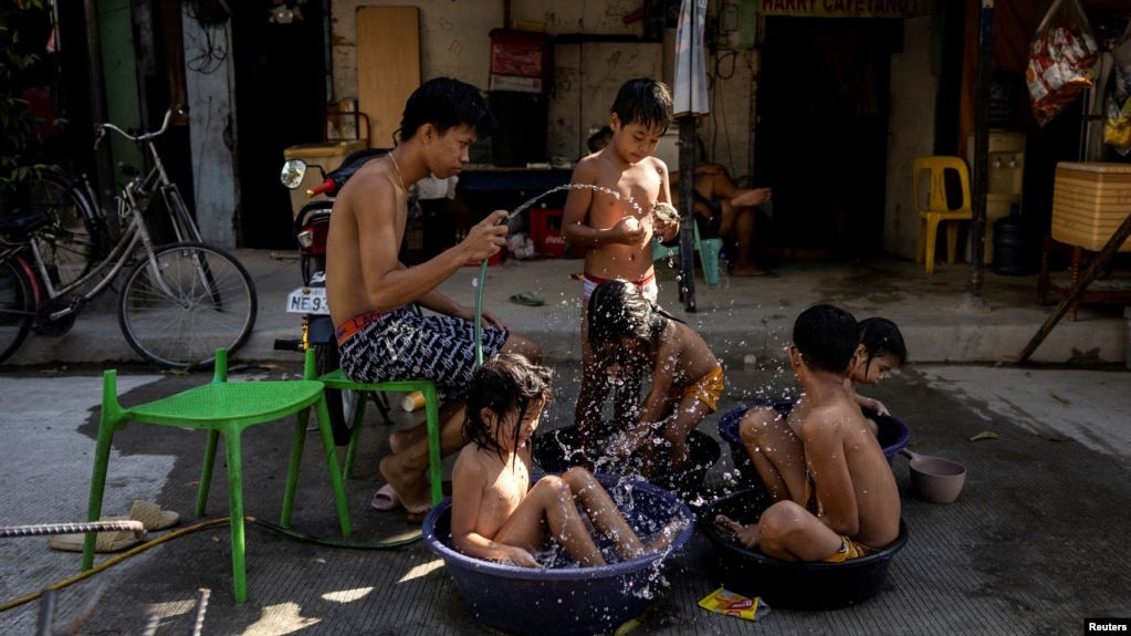 Children sit in buckets and basins during a hot day in Manila, Philippines, April 29, 2024. (REUTERS/Eloisa Lopez)