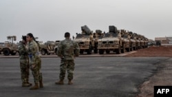 FILE - American soldiers stand in front of military vehicles to be loaded onto cargo planes in Niamey, Niger, June 7, 2024, as U.S. troops prepare for their withdrawal from the country.