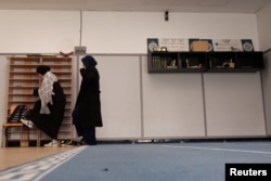 Students wearing abayas put their shoes back on as they prepare to leave the prayer room at the Averroes school, France's biggest Muslim educational institution that has lost its state funding, Lille, France, March 19, 2024.