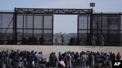 Un grupo de migrantes aguarda en Ciudad Juárez, México, junto al muro fronterizo con la esperanza de poder entrar en Estados Unidos el 30 de marzo de 2023.