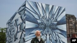 An elderly man passes an outdoor mural in Beijing, May 10, 2023.