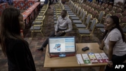 FILE - People stand beside a new voting machine to be used during the Democratic Republic of the Congo's (DRC) elections sits on a table beside on February 21, 2018 in Kinshasa, DRC. 