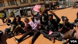 Chanting protesters sit in the middle of the road during protests in Kampala, Uganda, on July 23, 2024. (Halima Athumani/VOA)