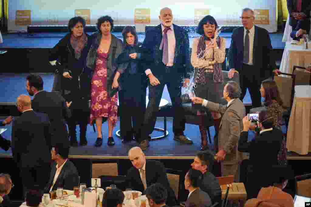 A man, third from right, throws water on climate activists protesting on a stage before Federal Reserve Chairman Jerome Powell speaks at a meeting of the Economic Club of New York.