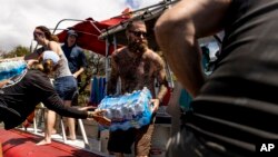 Volunteers load supplies onto a boat for West Maui at the Kihei boat landing, after a wildfire destroyed much of the historical town of Lahaina, on the island of Maui, Hawaii, Aug. 13, 2023. 