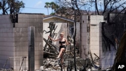 Sydney Carney walks through her home destroyed by a wildfire in Lahaina, Hawaii, Aug. 11, 2023.