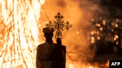 Un Grand Prêtre présente une croix devant un feu de joie lors des célébrations des vacances orthodoxes éthiopiennes de Meskel à Addis-Abeba le 27 septembre 2023.