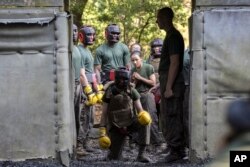 Female U.S. Marine Corps recruits stand behind a female recruit, kneeling, during a hand-to-hand combat drill in a portion of training known as the Crucible at the Marine Corps Recruit Depot, June 29, 2023, in Parris Island, S.C. (AP Photo/Stephen B. Morton)