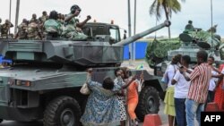 FILE - People wave and take pictures with men in uniform, moments after the swearing-in ceremony of Brice Oligui Nguema, inaugurated as Gabon's interim President, in Libreville on Sept. 4, 2023. 