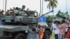 ARQUIVO - Pessoas acenam e tiram fotografias com homens fardados, momentos após a cerimónia de tomada de posse de Brice Oligui Nguema, como Presidente interino do Gabão, em Libreville, a 4 de setembro de 2023. 