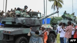 FILE - People wave and take pictures with men in uniform, moments after the swearing-in ceremony of Brice Oligui Nguema, inaugurated as Gabon's interim President, in Libreville on Sept. 4, 2023. 