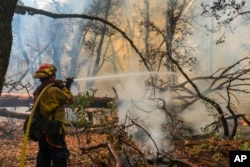 A firefighter sprays water on the Park Fire burning near Forest Ranch, Calif., July 27, 2024.