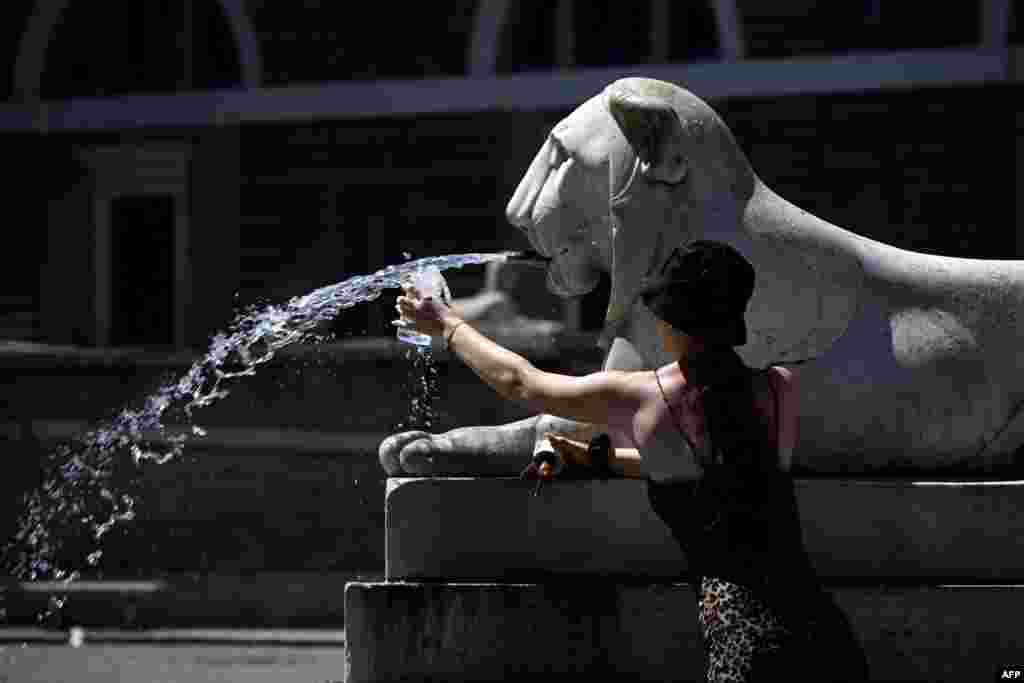 Seorang perempuan mengisi botolnya dengan air dari air mancur di Piazza del Popolo di Roma di mana suhu diperkirakan mencapai 36 derajat Celsius (97 derajat Fahrenheit). (AFP)&nbsp;