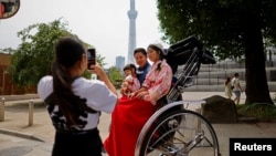 Penarik becak Akina Suzuki, 19 tahun, mengambil foto keluarga turis dari Taiwan selama ia menjadi pemandu tur bagi keluarga itu di sekitar distrik Asakusa di Tokyo, Jepang (foto: dok).