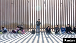 Migrantes esperan ser transportados por la patrulla fronteriza de Estados Unidos después de cruzar el muro fronterizo hacia desde México, mientras aumenta el número de migrantes en la ciudad fronteriza de Lukeville, Arizona, EEUU, el 12 de diciembre de 2023.