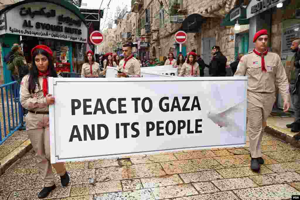 Niños palestinos desfilan en Belén, durante un día de Navidad lluvioso. Los adolescentes marcharon con carteles alusivos a la guerra en Gaza, poco antes de la llegada del Patriarca Latino de Jerusalén, Pierbattista Pizzaballa.