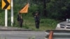 FILE - Members of the Karen state Border Guard Forces (BGF) standing guard on the Yangon-Myawaddy section of the Asia Highway road near Kawkareik township, Sept. 24, 2023. 