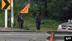 FILE - Members of the Karen state Border Guard Forces (BGF) standing guard on the Yangon-Myawaddy section of the Asia Highway road near Kawkareik township, Sept. 24, 2023. 