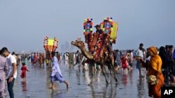 Families visit Clifton beach to celebrate the Eid al-Fitr holidays, marking the end of the Islamic holy fasting month of Ramadan, in Karachi, Pakistan.