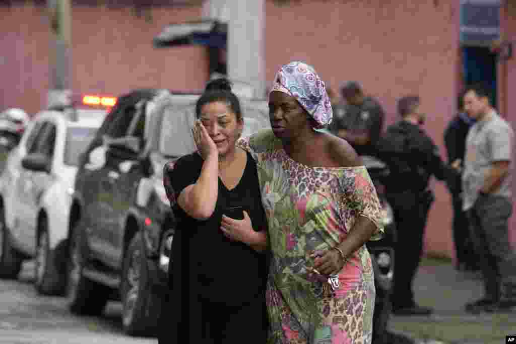 Silvia Palmieri, mother of a teacher who survived a stabbing attack at the Thomazia Montoro school, left, leaves the school comforted by a friend in Sao Paulo, Brazil.&nbsp;&nbsp;A 13-year-old student fatally stabbed a 71-year-old teacher and wounded three teachers and two fellow students in a knife attack at the public school, state officials said.