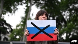 A protester holds a crossed out flag of Russia during a rally against the controversial "foreign influence" bill in Tbilisi, Georgia, on May 3, 2024.