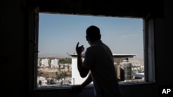 A relative of Mohammed Zalabani, a 13 year-old Palestinian awaiting trial for a Feb. 13 fatal stabbing attack, peers out a window of the family apartment which is slated to be demolished by Israeli authorities in Shuafat refugee camp in east Jerusalem, Aug. 30, 2023.