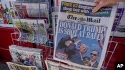 A woman buys a copy of the British Mail on Sunday newspaper at a news stand in London, July 14, 2024, showing the reaction to events at former U.S. President Donald Trump's campaign rally in Butler, Pennsylvania. 