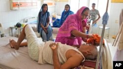 FILE: A woman wipes the head of her ailing brother to keep him cool from the heat wave by using a wet cloth at the district hospital in Ballia, Uttar Pradesh state, India, June 19, 2023. A scorching heat wave has overwhelmed hospitals and morgues. 