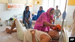 FILE - A woman wipes the head of her ailing brother to keep him cool from the heat wave by using a wet cloth at the district hospital in Ballia, Uttar Pradesh state, India, June 19, 2023. 