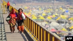 Devotees carry their belongings as they walk over a bridge during the annual religious Hindu festival of Magh Mela on the banks of Sangam in Prayagraj on Feb. 5, 2023. In 2018, Prayagraj's name was changed from Allahabad. 