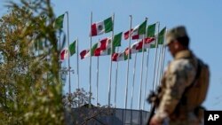 A guardsman keeps watch along the Rio Grande with flags seen on the Mexico side, in Eagle Pass, Texas, Jan. 3, 2024.