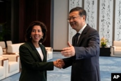 FILE - Shanghai Party Secretary Chen Jining gestures as he shakes hands with U.S. Commerce Secretary Gina Raimondo before a meeting in Shanghai, China, on Aug. 30, 2023.