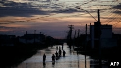 People walk along a flooded street of Eldorado do Sul, Rio Grande do Sul, Brazil, on May 9, 2024. 